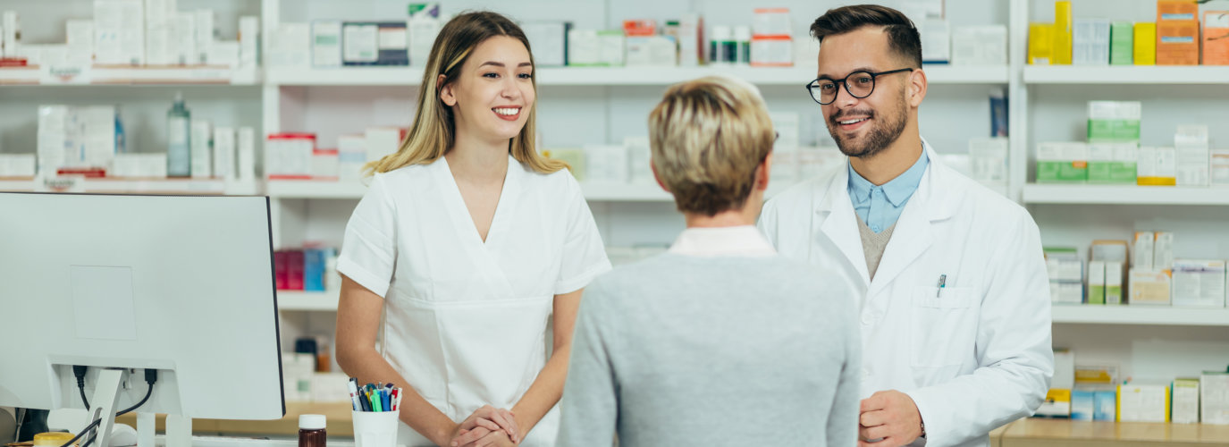 Two pharmacist giving prescription medications to senior female customer in a pharmacy