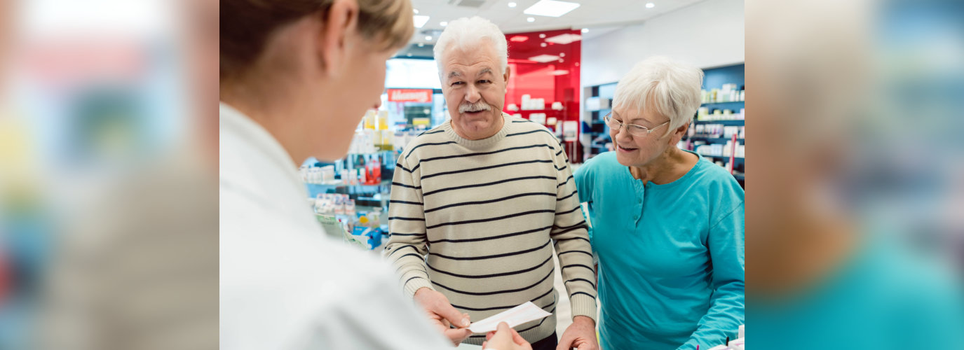 Pharmacist getting prescription slip from senior couple in her pharmacy