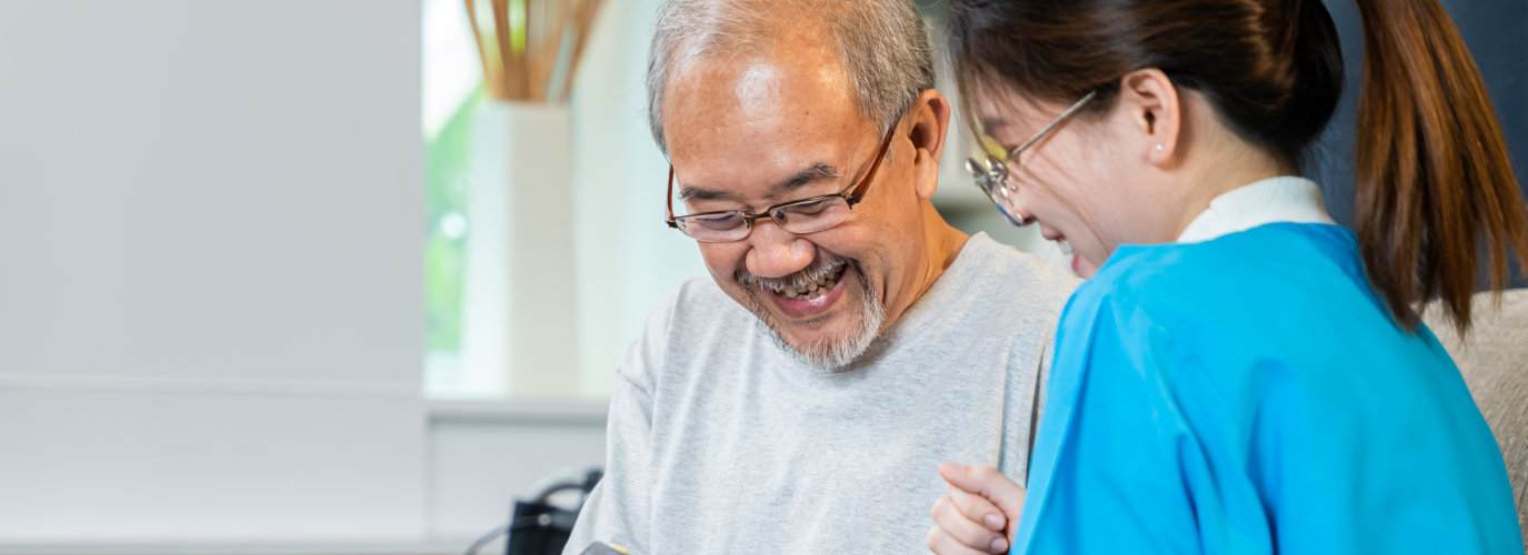 elderly man and caregiver laughing
